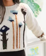 Sweater de punto color blanco con diseño de hongos bordados en tonos azules, marrones y celestes, de manga larga y cuello redondo.