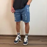 Bermuda de jean estilo jogger con efecto desgastado, roturas frontales y ruedo desflecado.