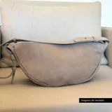 Bandolera de cuero color beige con correa ajustable y cierre superior con cremallera.