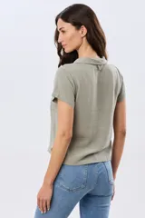 Camisa lisa de lino color beige, de manga corta, con cuello camisero, bolsillo ojal en el pecho y cierre frontal con botones.