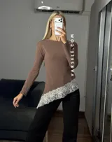Blusa de manga larga color marrón, con corte asimétrico y detalle de puntilla blanca en el ruedo. Confeccionada en tejido de algodón y viscosa.