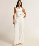Pantalón de vestir blanco, de corte palazzo, con trabillas en la cintura, bolsillos laterales y pliegues delanteros.