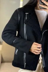 Campera tipo gamulán de color crema con interior y cuello de corderito sintético. Presenta cierre frontal cruzado, bolsillos laterales con cierre y detalles de costuras en contraste color marrón oscuro.