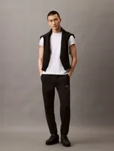 Pantalón de jogging negro con cintura elástica y logo monograma de Calvin Klein en color gris claro en el muslo izquierdo.
