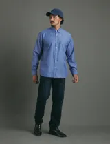 Camisa de vestir de corte clásico, color azul, con cuello italiano, cierre frontal de botones y bolsillo en el pecho.