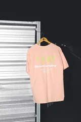 Remera color salmón de corte oversize, con estampa en la espalda con el logo de la marca y horario de delivery.