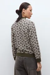 Campera bomber verde oliva con estampado geométrico en blanco, cuello, puños y cintura elásticos.