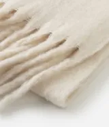 Bufanda de punto suave y voluminosa, color blanco, con diseño de textura esponjosa y flecos en los extremos.