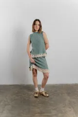 Conjunto de top sin mangas y minifalda a rayas color verde agua y blanco, con flecos en el ruedo. Tejido confeccionado en Uruguay con 50% poliéster y 50% algodón.