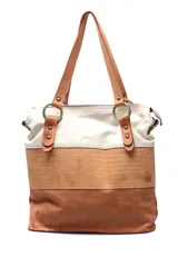 Cartera tipo tote de cuero con diseño tricolor, combinando secciones en color crema, textura croco en tono tostado y base en cuero liso marrón. Cuenta con doble asa de hombro sujeta por argollas metálicas y detalles de tachas decorativas.