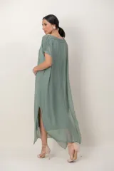Vestido largo de seda color verde seco, con transparencias en el ruedo, mangas cortas y detalle de guarda bordada con lentejuelas en hombros y mangas.