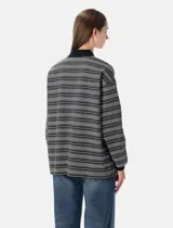 Remera polo de manga larga con diseño de rayas horizontales en tonos grises, blancos y negros. Presenta cuello clásico y puños en color negro sólido, tapeta con botones y logo bordado en el pecho.