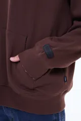 Buzo tipo canguro de felpa color gris, con capucha amplia, bolsillo frontal tipo canguro y puños acanalados.