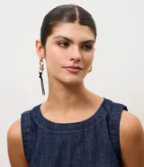 Par de aros colgantes asimétricos de metal dorado con diseño moderno. Un aro presenta una argolla orgánica texturizada y el otro combina eslabones de cadena con un cordón doble negro con punteras metálicas.