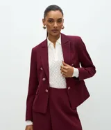 Blazer de sastrería entallado de color bordó, con solapas de muesca, cierre cruzado de botones dorados y bolsillos con solapa en los laterales.