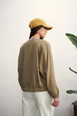 Chaqueta tipo bomber color negro, con cierre frontal metálico, cuello redondo y puños elásticos.