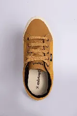 Zapatillas casuales color mostaza con cordones negros y suela blanca.