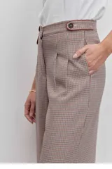 Pantalon de vestir de corte sastrero y pierna ancha, con estampado de cuadros tipo príncipe de gales en tonos tierra. Presenta cintura alta con trabillas, cierre frontal con botones y bolsillos laterales con detalle de ribete.