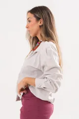 Camisa beige a rayas finas de manga larga, con cuello camisero y cierre frontal oculto.