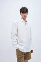 Camisa celeste de algodón, corte regular fit, con cuello solapa clásico, manga larga, bolsillo en el pecho y botones personalizados.