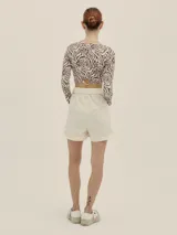 Shorts celestes a rayas verticales, de tiro alto y corte holgado, con pinzas en el frente y detalle de Polonio en cobre.