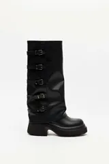 Bota alta de cuero sintético negro con suela track, tacón chunky y cinco tiras con hebillas metálicas en el lateral de la caña.