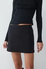 Minifalda negra de tiro medio confeccionada en tejido crepé, con silueta recta y diseño minimalista.