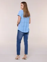 Blusa celeste de tejido pointelle calado, con escote redondo, mangas cortas con dobladillo y presilla con botón, y ruedo curvo.