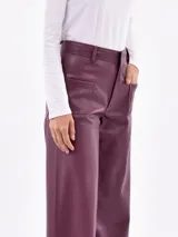 Pantalón de corte ancho y relajado, confeccionado en cuero sintético color borravino. Cuenta con bolsillos frontales aplicados de diseño geométrico, tiro alto y trabillas para cinturón.