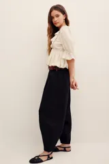 Pantalón babucha negro de lino, de corte holgado estilo barrel con pinzas en la cintura y bolsillos laterales.