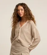 Cardigan color beige confeccionado en tejido de punto con lentejuelas, de corte regular, cuello en V, manga larga y cierre abotonado frontal.