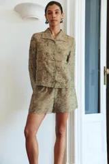 Camisa de cupro color verde militar con estampado jacquard de patrones florales y geométricos. Presenta cuello solapa, manga larga y cierre frontal con botones.