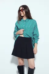 Minifalda tableada de color negro, con diseño de tablas anchas que aportan volumen y movimiento. Presenta un corte estructurado y un calce cómodo.