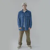 Camisa azul de pana con corte oversize, cuello clásico, cierre frontal con botones, mangas largas con puños abotonados y dos bolsillos con solapa abotonada en el pecho.