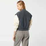 Campera bomber azul petróleo acolchada con cuello redondo, cierre con botones a presión, bolsillos con solapa y puños y cintura elásticos.