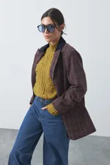 Blazer de corte relajado con estampado de cuadros tipo pied de poule en tonos rojizos y verdes. Presenta solapas clásicas en color azul oscuro y estructura definida.
