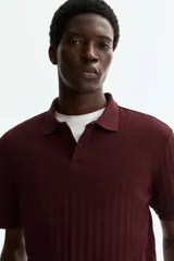 Remera polo de punto texturizado color bordó, de manga corta, con cuello y tapeta de dos botones. Corte ajustado slim fit.