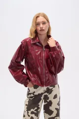 Chaqueta corta de cuero sintético negro con cuello camisero, cierre frontal con cremallera, bolsillos laterales y mangas largas abullonadas.