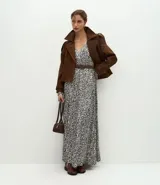 Vestido midi de tejido satinado con estampado abstracto, escote en V, mangas largas con volumen y hombreras estructuradas. Incluye un cinturón con hebilla para marcar la cintura y falda fluida con recortes.