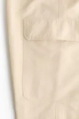 Pantalón cargo de nylon de corte oversized con leve efecto arrugado, cintura elástica fruncida, bolsillos con cierre en el frente y bolsillos con solapa en las piernas.