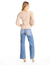 Buzo de tejido lurex en color beige, con cuello redondo y mangas largas con diseño plisado y puños con aplique de botones dorados.