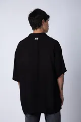 Camisa de manga corta con cuello cubano, confeccionada en fibrana premium. Presenta un corte oversize y cierre frontal con botones al tono.