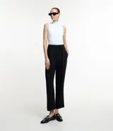 Pantalón de vestir negro, modelo carrot (holgado en cadera y ajustado en tobillo), confeccionado en terciopelo, con lazo ajustable en la cintura y pliegues frontales.