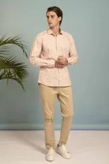 Camisa de manga larga en color salmón con estampado de pequeños motivos geométricos oscuros, cuello clásico y cierre frontal con botones.