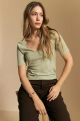 Top de manga corta confeccionado en tejido jacquard con textura en relieve. Presenta escote en V y un diseño frontal con líneas diagonales que crean un efecto cruzado.