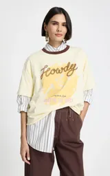 Remera de algodón color beige con cuello redondo en contraste marrón. Presenta mangas cortas y un estampado frontal con temática western que incluye letras y una ilustración central.