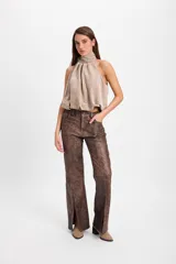 Pantalón de cuero color chocolate con efecto desgastado, de corte recto y tiro medio. Presenta costuras verticales en el frente y tajos laterales en el ruedo que aportan movimiento.