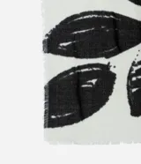 Bufanda confeccionada en franela de acrílico con flecos y estampa de follajes en blanco y negro.