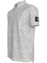 Chomba gris jaspeado de piqué de algodón peinado, con cuello clásico y tapeta de dos botones. Tiene mangas cortas, dobladillo con aberturas laterales y logo de Calvin Klein en la manga.