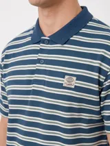 Chomba Rusty modelo Baviera de corte holgado, con diseño a rayas horizontales en tonos azul y beige. Cuenta con cuello mao, cierre frontal con botones y parche bordado con logo en el pecho.